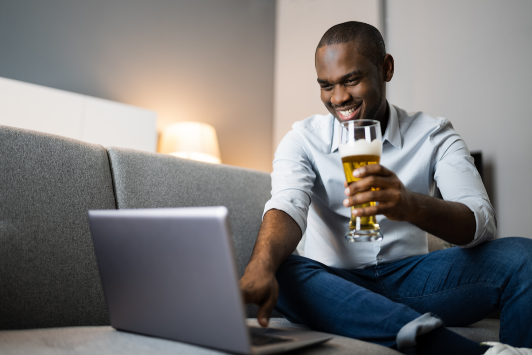 man sitting in front of computer drinking beer